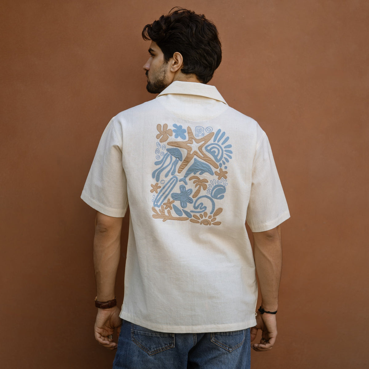 Back view of Sea Drift khadi shirt with hand-appliqued starfish, dolphin and palm artwork
