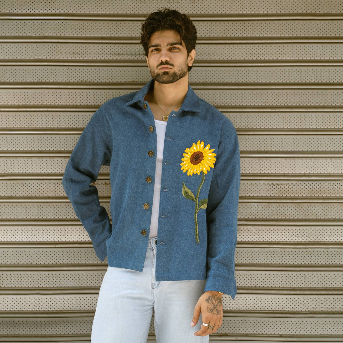 Man wearing mid blue denim shaket with hand-embroidered French knot sunflower, front view