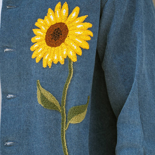 Close-up of hand-embroidered French knot sunflower on blue denim shaket
